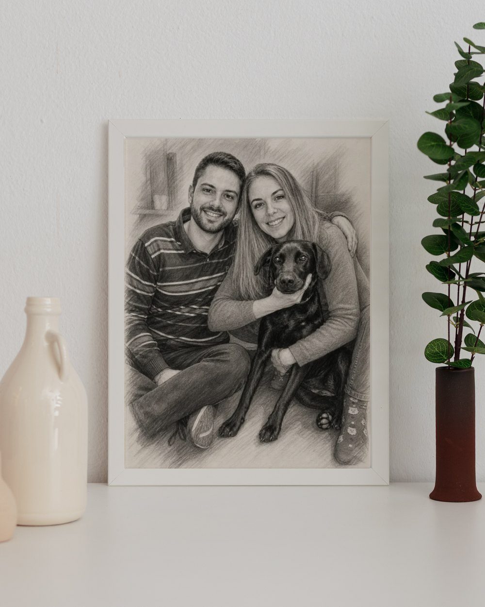 Retrato a carboncillo de una pareja con su labrador, enmarcado en blanco